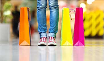 Colourful shopping bags on the floor by a shoppers feet