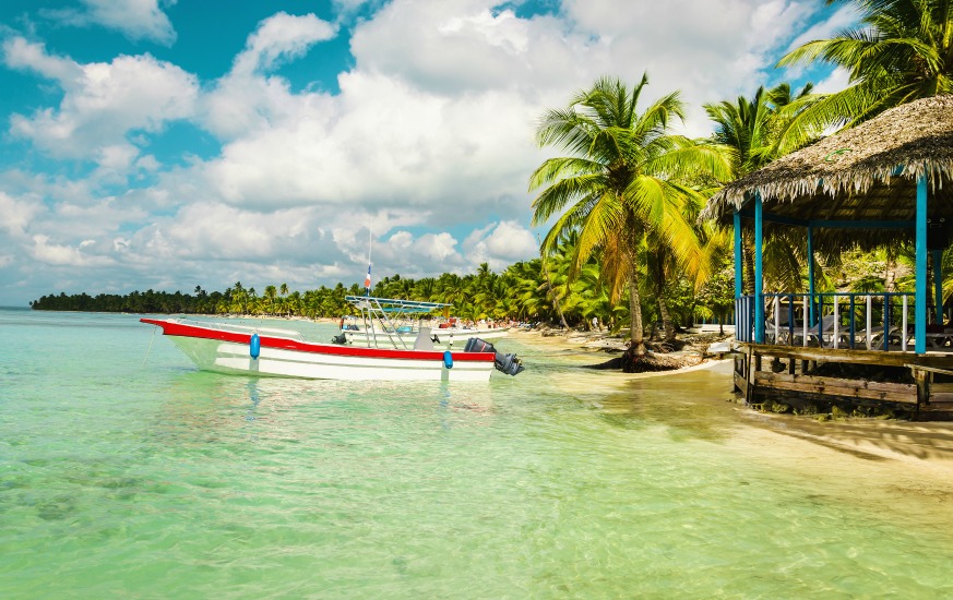 Boat moored off the coast of the island full of palm trees, Caribbean Islands