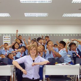 i-to-i TEFL teacher kneeling in front of desk rows with pupils