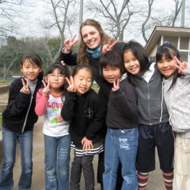 i-to-i TEFL intern with pupils in playground smiling for camera