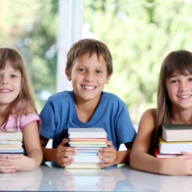 3 young TEFL students with books smiling at camera