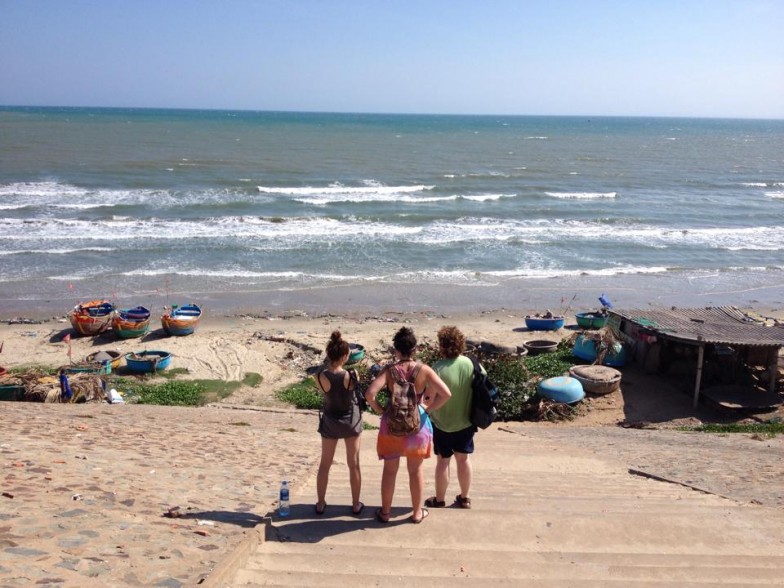 Three women on beach in Thailand looking at boats