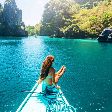 girl sat on a boat on bright blue sea