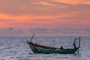 boat out at sea with sunset behind