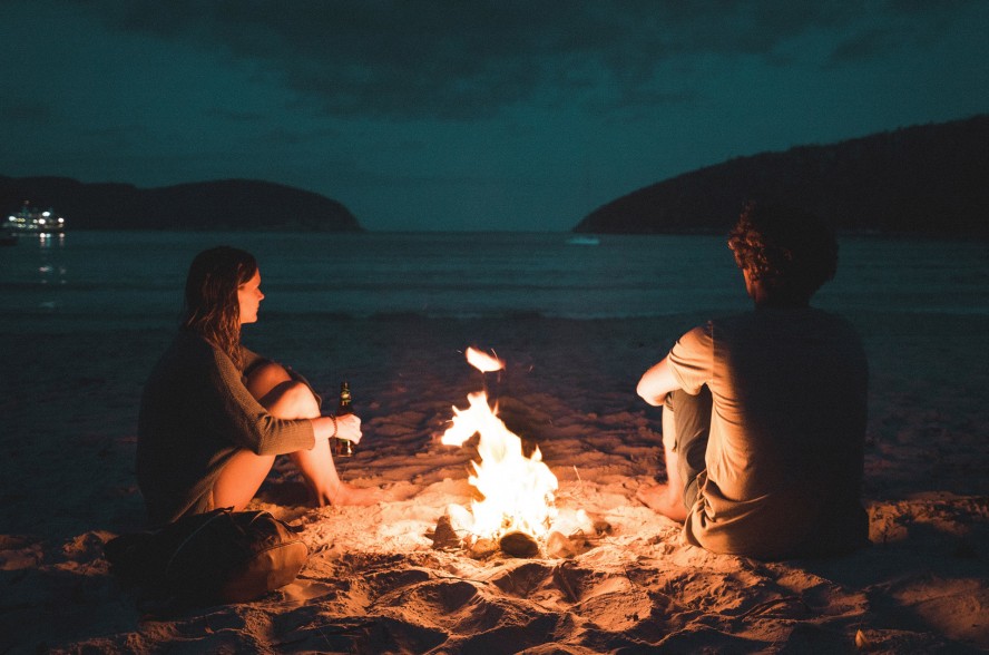 a couple next to a fire on the beach