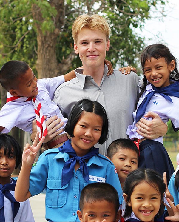 Male teacher in school yard with thai school children