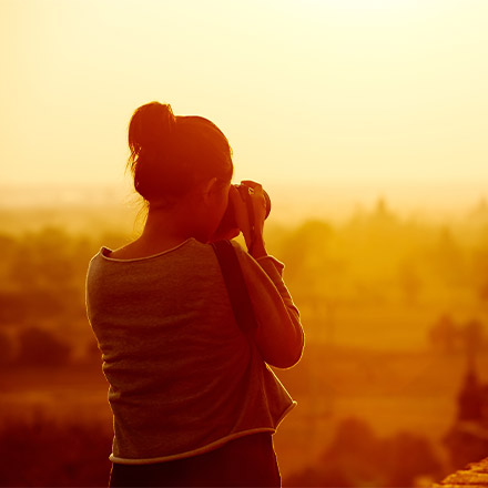 Woman taking photo at sunset