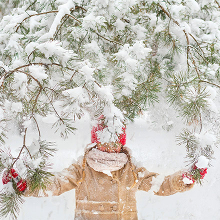 Girl under snow covered tree