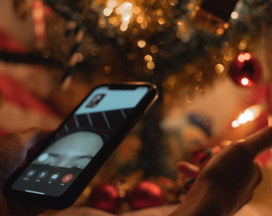 Person holding phone making video call in front of Christmas tree