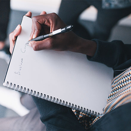 Business woman writing in notepad