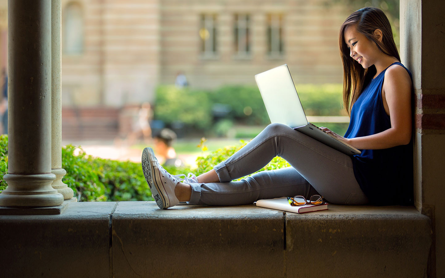 Girl sitting in school and studying on her laptop and smiling