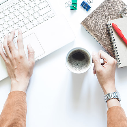 Businesswoman using laptop and drinking coffee