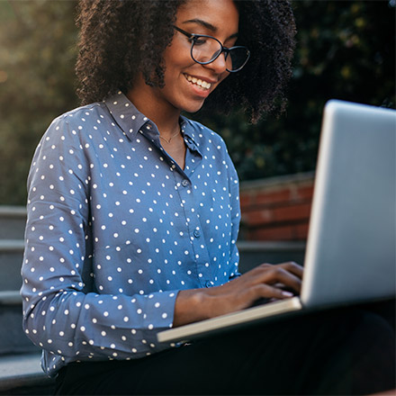 Business woman sat outside typing on laptop