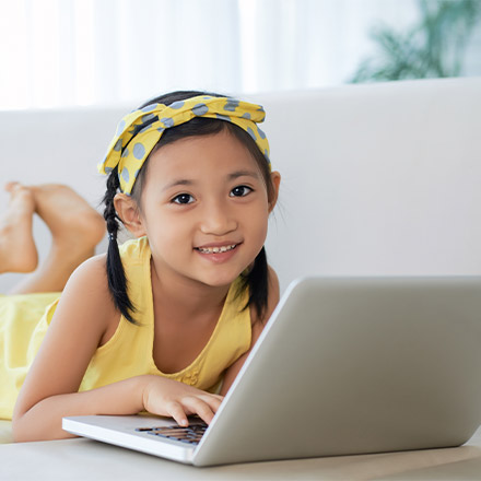 Girl laid on sofa using laptop