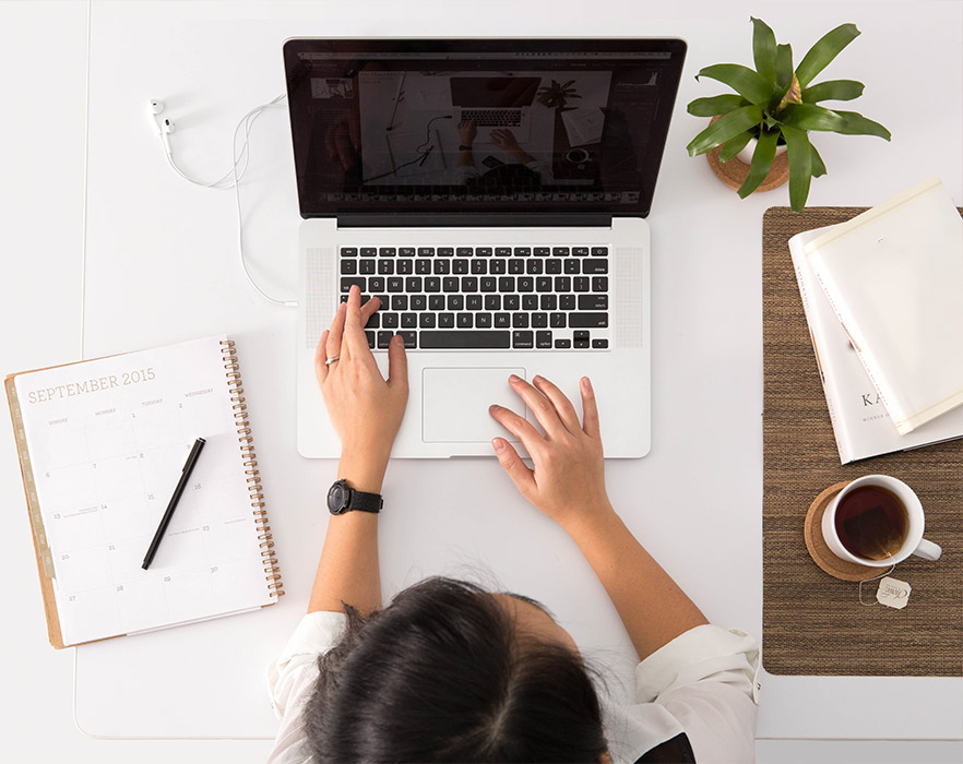 Woman sat at desk typing on laptop