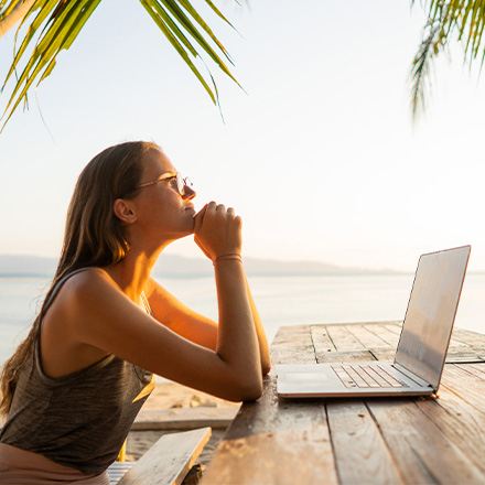 Woman sat on a bench using latop near beach