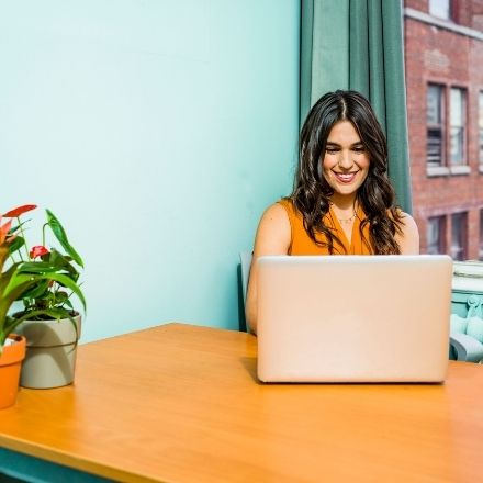 woman job hunting on pink laptop