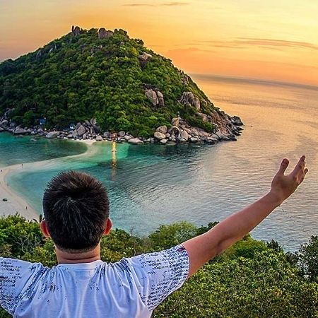 man with arms open looking out over sunset