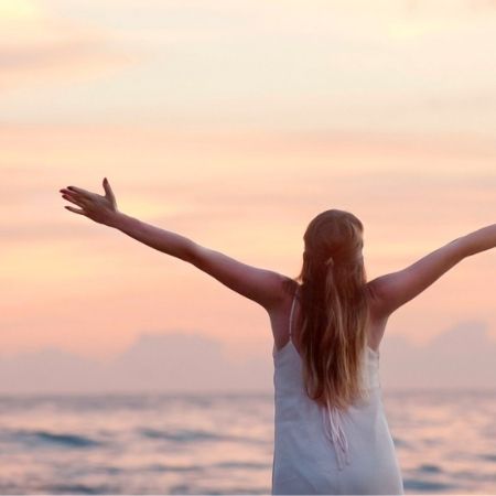 woman with arms open looking at the sunset