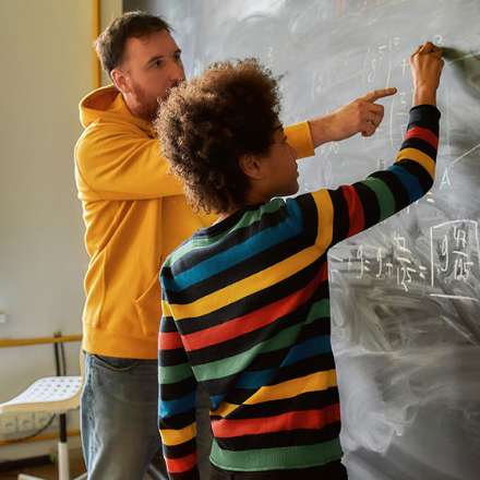 quality of a good teacher man with student pointing to blackboard