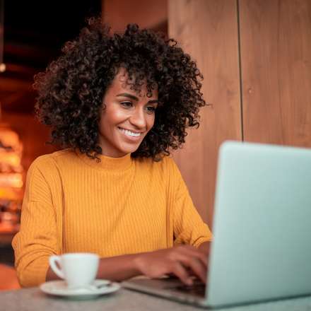 WOMAN SMILING AT LAPTOP